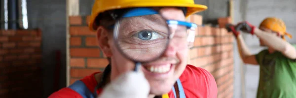 Construtor sorridente em uniforme examinando cuidadosamente o trabalho acabado — Fotografia de Stock