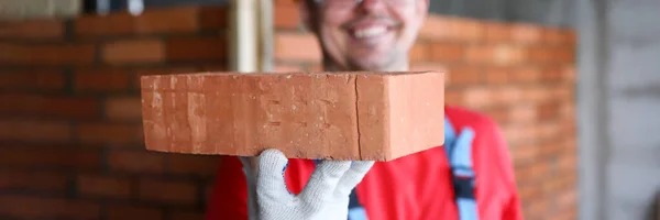 Sorrindo construtor masculino mostrando material de tijolo de qualidade fina na câmera — Fotografia de Stock