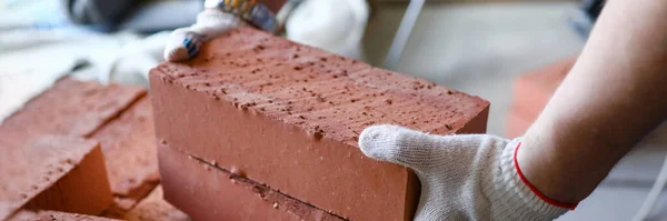 Mãos masculinas levantando vários tijolos vermelhos no local de construção — Fotografia de Stock