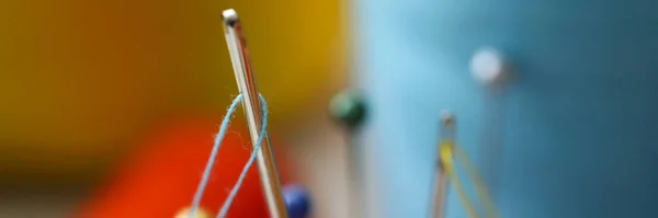 Nålöga med bit blå tråd sticka ut ur nålkudden — Stockfoto