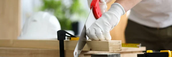 Человек в перчатках распиливает деревянные детали на верстаке — стоковое фото
