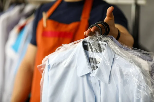 Працівник служби хімчистки одягу повертає сорочки клієнту — стокове фото