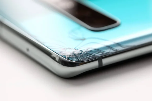 Modern smartphone lying at table with crack in corner — Stockfoto