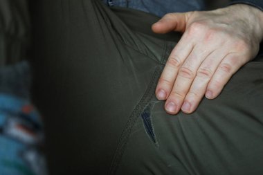 Bacakları açık, pantolonunda delikler olan bir adam.