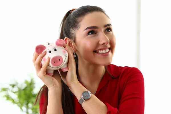 Portret młodej pięknej brunetki trzymającej różowe pudełko dla pieniędzy — Zdjęcie stockowe