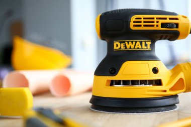 DeWALT zımpara makinesi ahşap masada yakın çekim için hazır bekliyor.