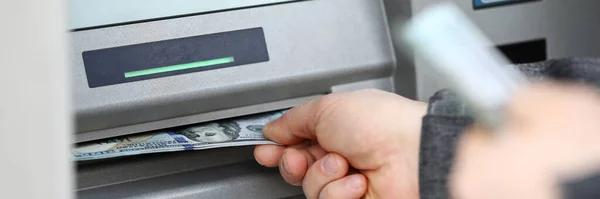 Male hands holding bunch of hundred dollars banknotes at atm machine — 스톡 사진