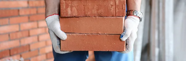 Gloved builder manually carries brick construction — 스톡 사진