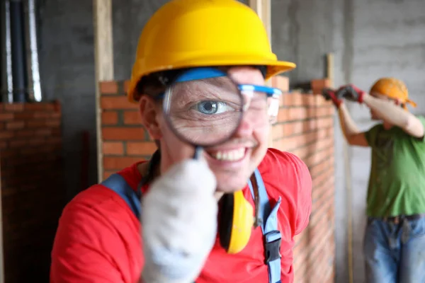 Construtor sorridente em uniforme examinando cuidadosamente o trabalho acabado — Fotografia de Stock