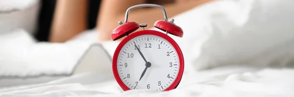 Red alarm clock showing five before seven — Stockfoto