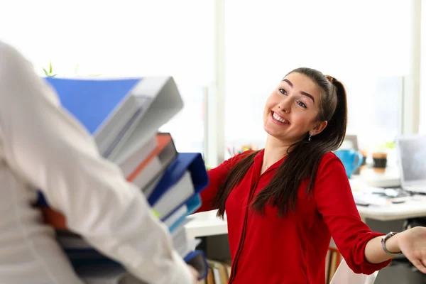 Jonge gelukkige vrouw zittend in functie en begroet collega met een hoop documenten — Stockfoto