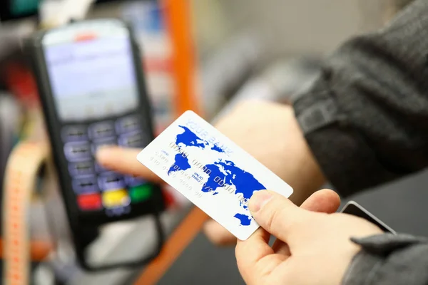 Чоловіча рука тримає банківську картку при оплаті за допомогою каси супермаркету — стокове фото