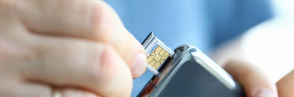 Mannelijke handen krijgen sim card slot van zijn smartphone uit — Stockfoto