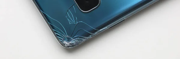 Modern smartphone lying at table with crack in corner — Stockfoto