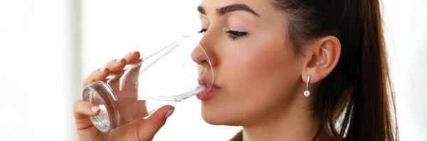 Beautiful girl at work drinks water from glass — Stock Photo, Image