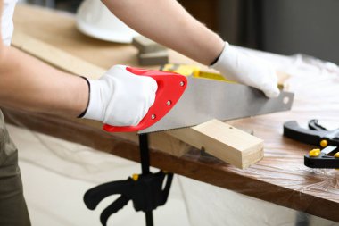 Carpenter uses saw which is sawing across at angle