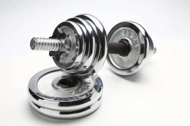 Gümüş renkli, parlak, metal bir halter yığını üzerinde duruyor.