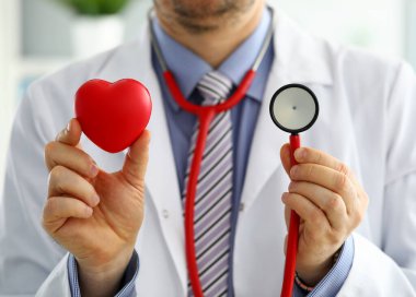 Male medicine doctor holding red heart and stethoscope clipart