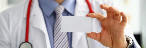 Männlicher Arzt hält leere Visitenkarte in der Hand — Stockfoto