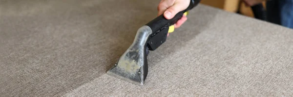 Male housekeeper arm cleaning sofa with washing vacuum cleaner — Stock Photo, Image