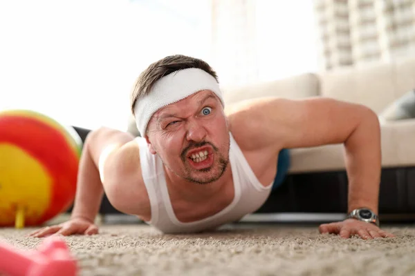 Homme grimaçant drôle faisant push-ups maison — Photo