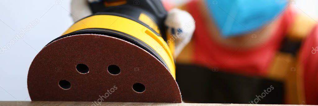 Masked carpenter grinds wood with sander machine — Stock Image Masked carpenter grinds wood with sander machine Royalty Free Stock Images