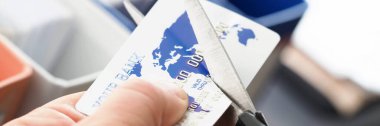 Erkek el makasla bankacılık kartını kesiyor.
