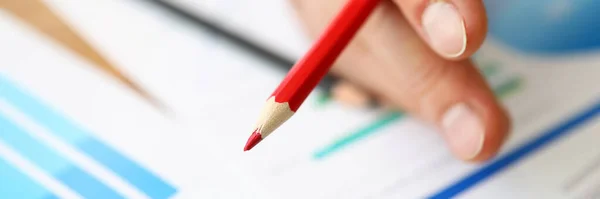 Dedos segurar lápis vermelho em diagramas de fundo — Fotografia de Stock