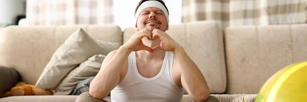 Guy sits at home carpet meditates and shows heart — Stock Photo, Image