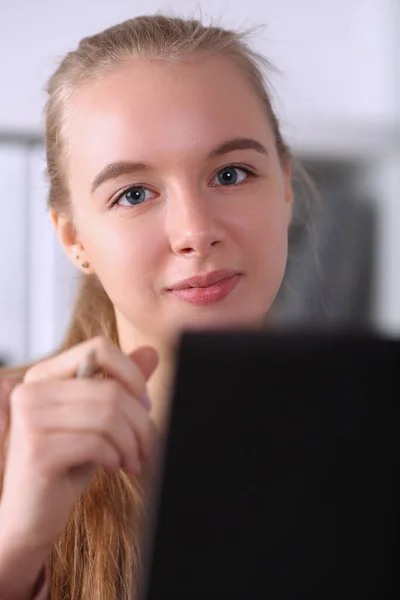 Mooi meisje houdt pen zit naast laptop — Stockfoto