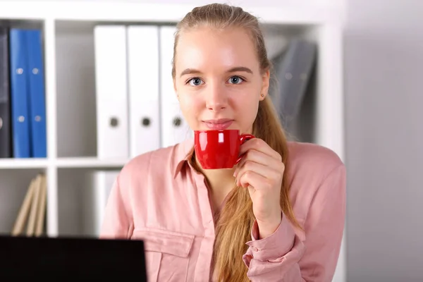 Menina senta-se computador frente do escritório e bebe café — Fotografia de Stock