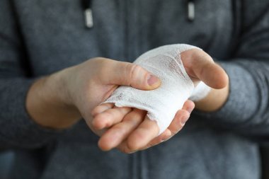 Yaralı kol beyaz bandajla sarılmış.