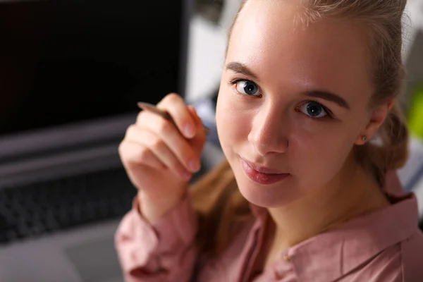 Meisje op kantoor zit in de voorkant laptop en houdt pen — Stockfoto
