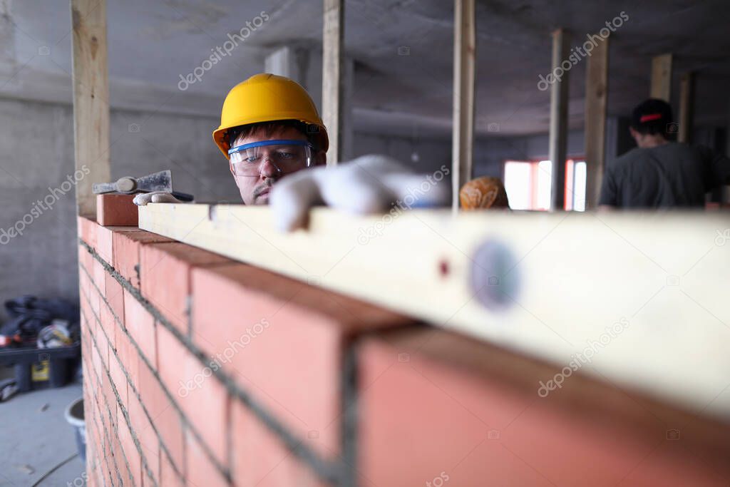 Construction guy helmet measures level brickwork
