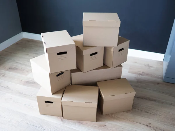 Stapel kartonnen dozen in het midden van een lege kamer in een nieuw huis — Stockfoto