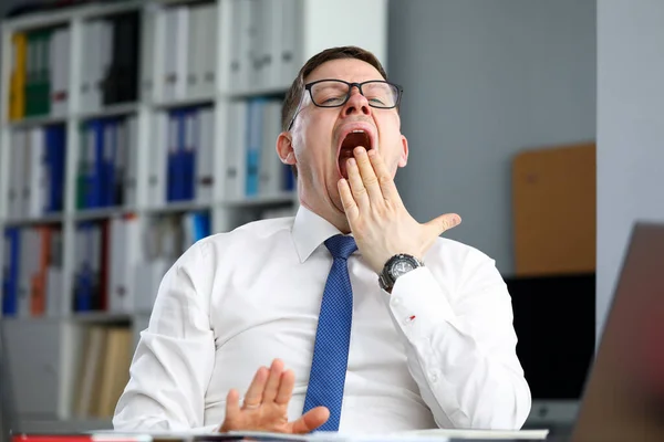 Oficina de hombre de negocios cansado se sienta a la mesa y bosteza — Foto de Stock