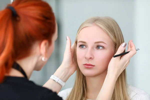 Make-up kunstenaar kijkt naar symmetrie modellen wenkbrauwen — Stockfoto