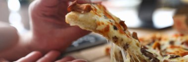 Erkek kolları büyük bir dilim taze pizza alıyor.