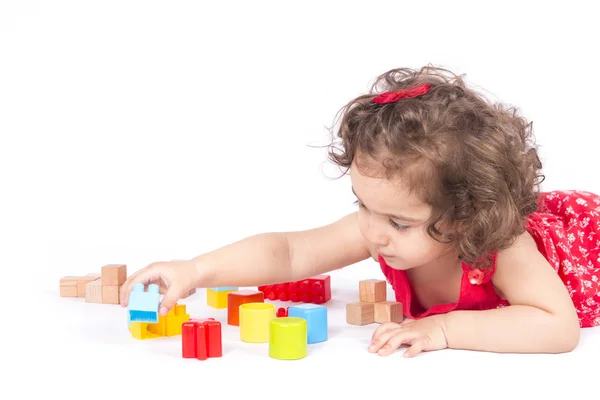 Meisje in de rode jurk speelt met game cube op de verdieping — Stockfoto