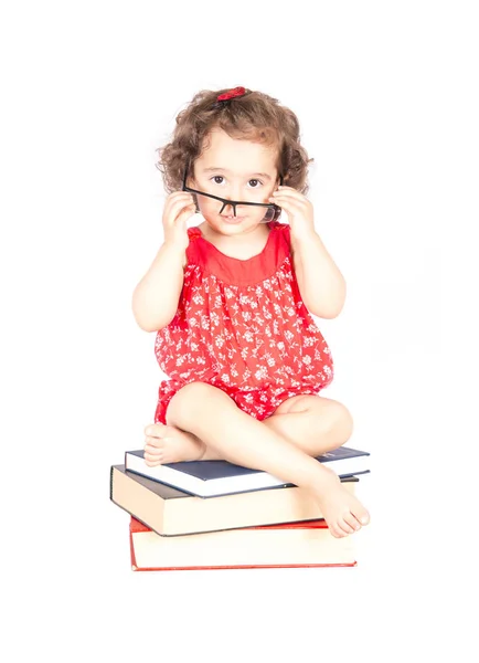 Meisje, zittend op boeken — Stockfoto