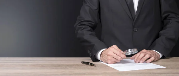 işadamı bir büyüteç ile belge analiz ediyor