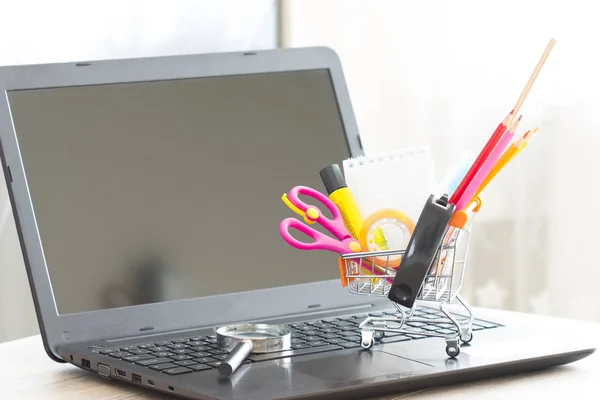 Escola e material de papelaria em laptop carrinho de compras top — Fotografia de Stock