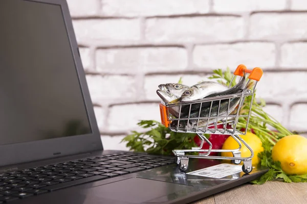 Peixe no carrinho de compras e laptop — Fotografia de Stock