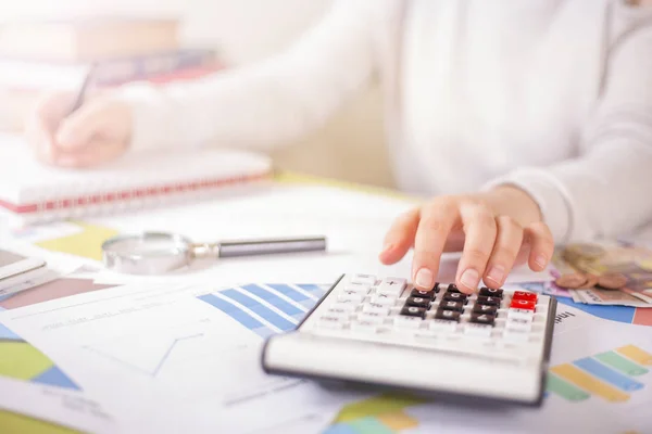 Mujer está haciendo cálculos en el escritorio de la oficina —  Fotos de Stock