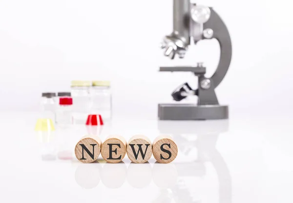 Writing news front of microscope and test tubes for health and s — Stock Photo, Image