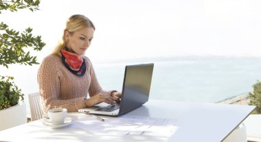 Beyaz tenli sarışın kadın dışarıda kucağıyla çalışıyor.