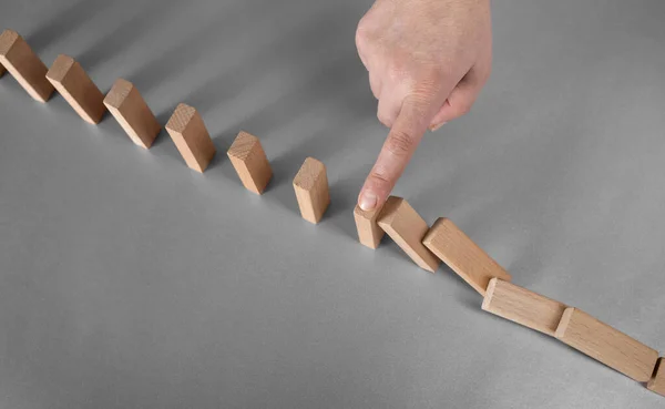 domino effect prevention concept. finger stops falling dominoes