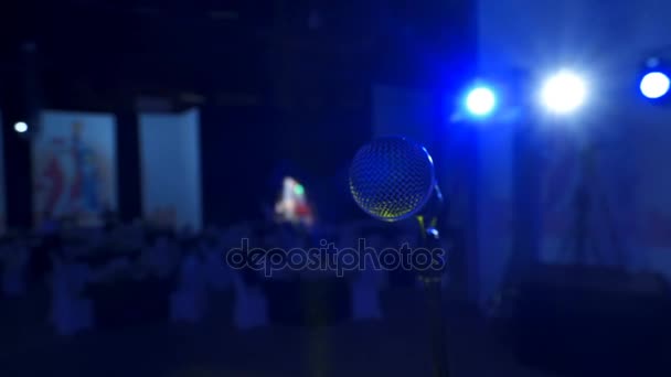 4K. Vocal microphone with stand on big stage in hall of auditorium or atrium with blue soffit at the bg. — Stock Video