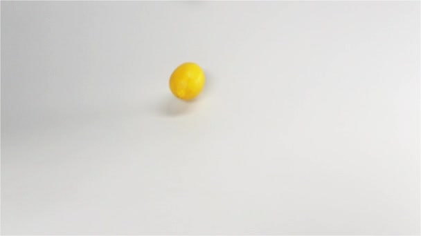 Fresh yellow lemons falling down on white surface — Stock Video