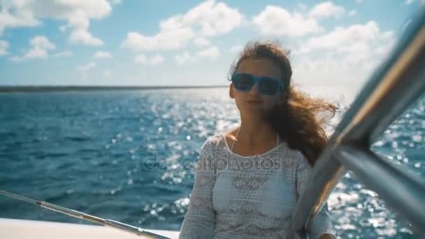 Fille en lunettes de soleil assis sur le bord du yacht au milieu de la mer — Video